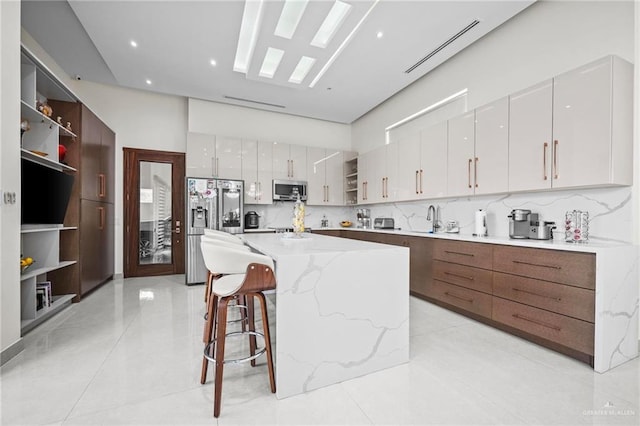 kitchen with white cabinetry, stainless steel appliances, a breakfast bar area, and a kitchen island