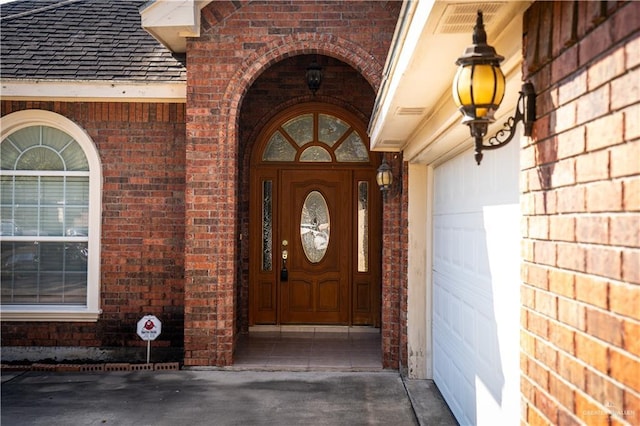 entrance to property with brick siding and a shingled roof