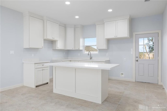 kitchen with baseboards, recessed lighting, white cabinetry, and a center island