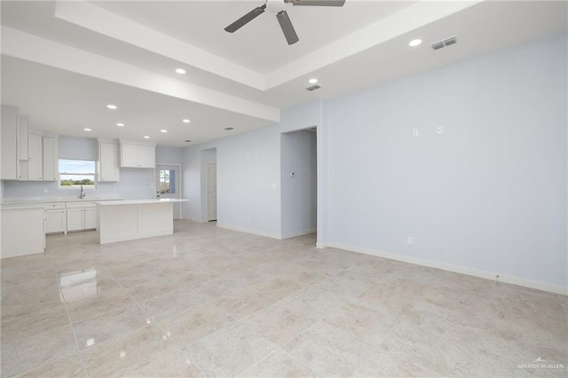 unfurnished living room with recessed lighting, a sink, visible vents, baseboards, and a raised ceiling