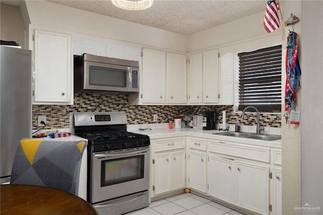 kitchen with stainless steel appliances, light countertops, decorative backsplash, a sink, and a textured ceiling