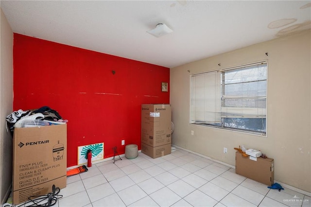 bedroom featuring an accent wall and light tile patterned flooring