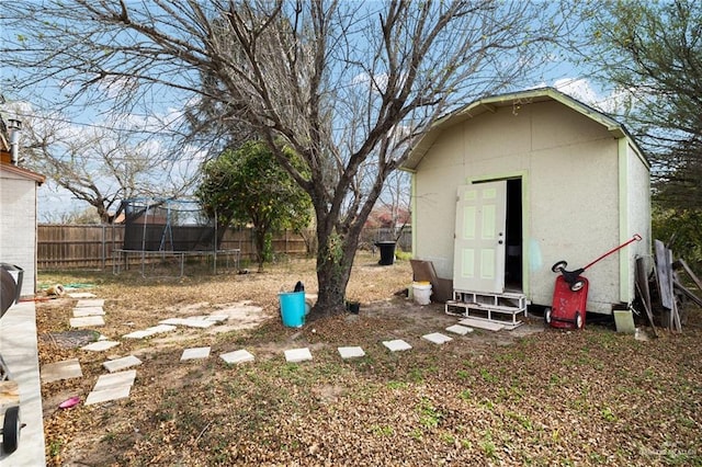 view of yard with an outbuilding, a storage unit, a trampoline, and a fenced backyard