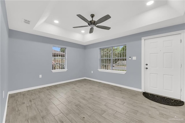 entryway with ceiling fan and a raised ceiling