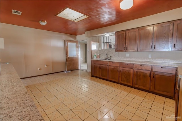 kitchen featuring light countertops, visible vents, and brown cabinets