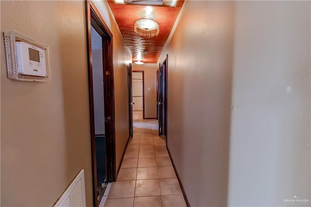 hallway featuring light tile patterned floors, visible vents, and baseboards