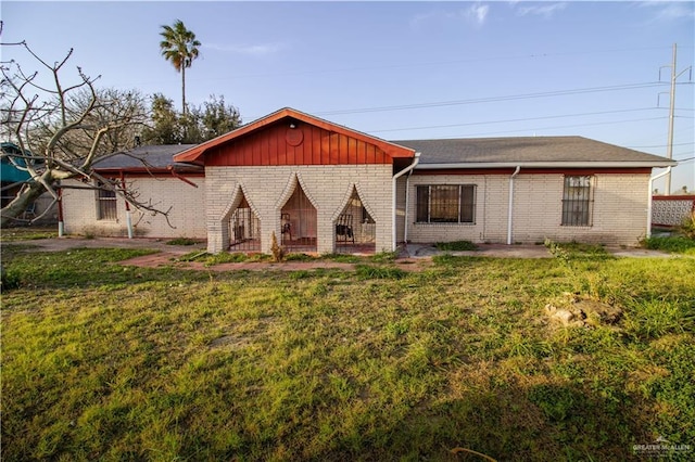 ranch-style home with brick siding, a front yard, and a patio area