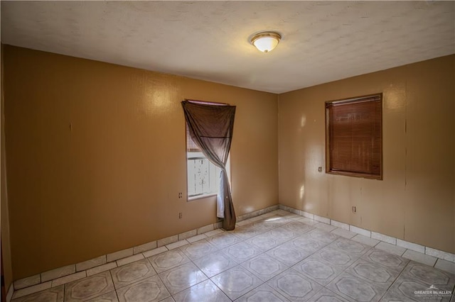 unfurnished room with light tile patterned floors and baseboards