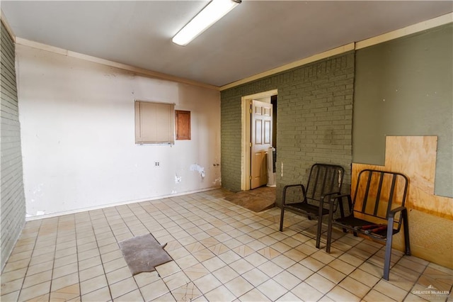 unfurnished room with light tile patterned floors, brick wall, and ornamental molding