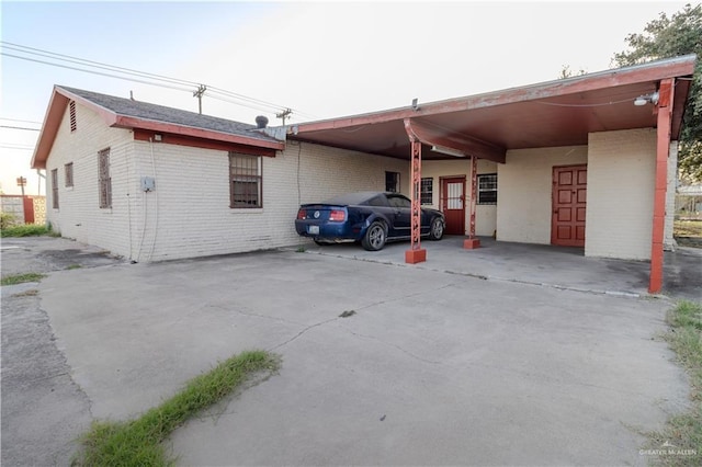 exterior space featuring brick siding, an attached carport, and driveway