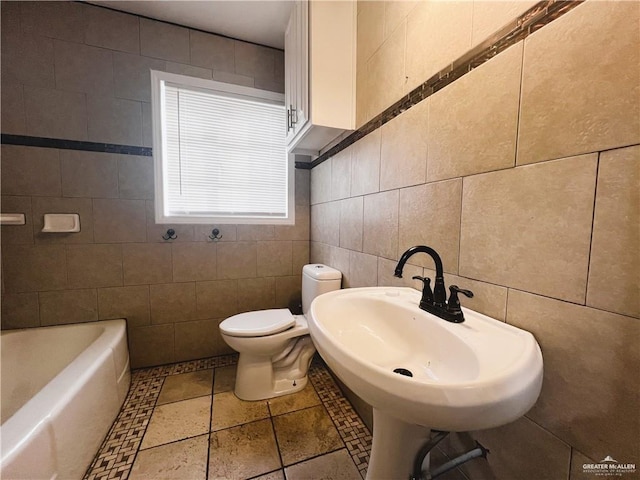 bathroom featuring a tub to relax in, sink, tile walls, and toilet