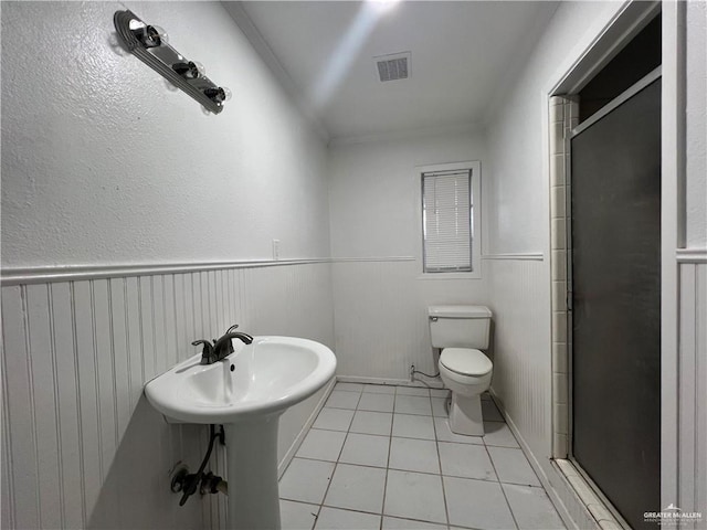 bathroom featuring tile patterned flooring, toilet, and a shower with shower door