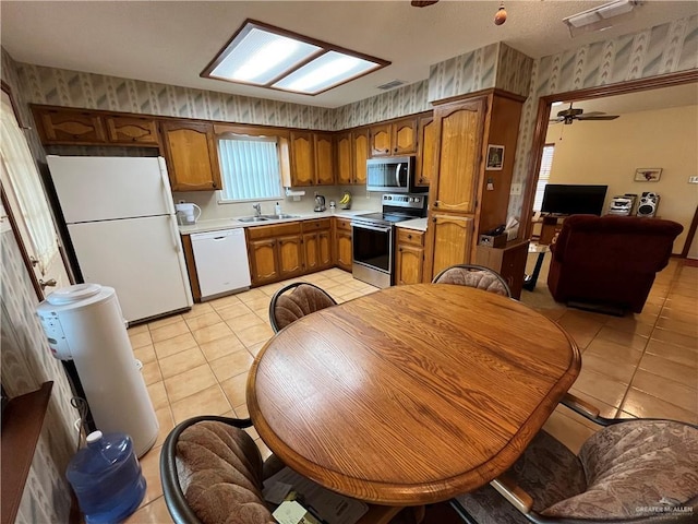 kitchen with stainless steel appliances, a sink, light countertops, and wallpapered walls