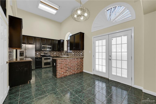 kitchen with french doors, stainless steel appliances, dark brown cabinets, high vaulted ceiling, and tasteful backsplash