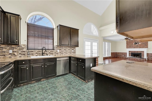 kitchen featuring appliances with stainless steel finishes, sink, ceiling fan, a fireplace, and french doors