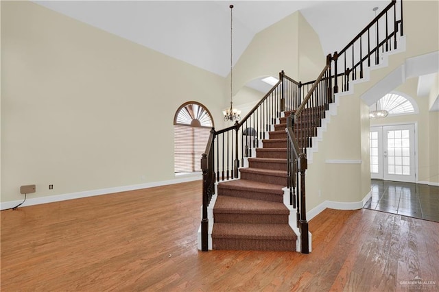 foyer entrance featuring high vaulted ceiling, french doors, wood-type flooring, and a notable chandelier