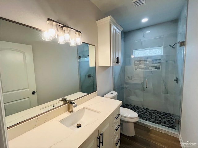 bathroom featuring toilet, a shower with door, and vanity