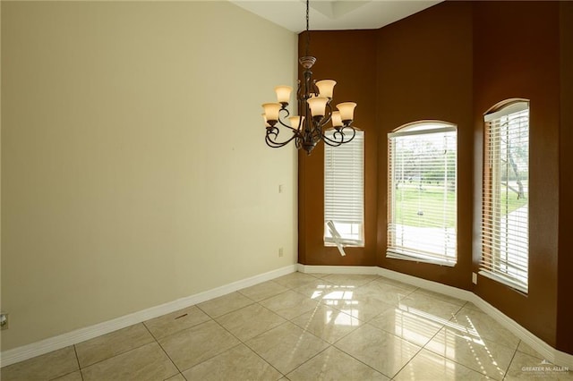 tiled spare room featuring a notable chandelier