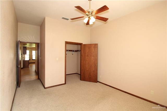 unfurnished bedroom featuring a walk in closet, ceiling fan, a closet, and light colored carpet