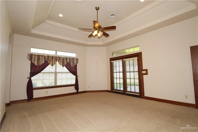 unfurnished room featuring carpet, plenty of natural light, ceiling fan, and a raised ceiling