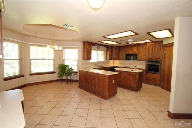 kitchen with a center island, stainless steel oven, ceiling fan with notable chandelier, hanging light fixtures, and light tile patterned floors