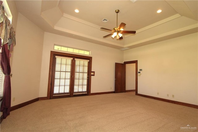 carpeted empty room featuring ceiling fan and a raised ceiling