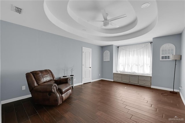 sitting room featuring dark hardwood / wood-style floors, a raised ceiling, and ceiling fan