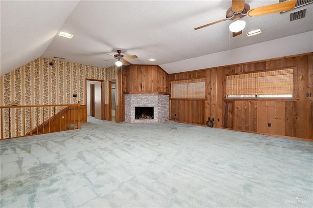 unfurnished living room with carpet floors, a brick fireplace, ceiling fan, and lofted ceiling