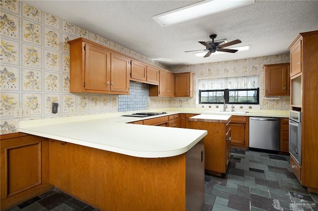 kitchen with kitchen peninsula, a textured ceiling, stainless steel appliances, ceiling fan, and sink