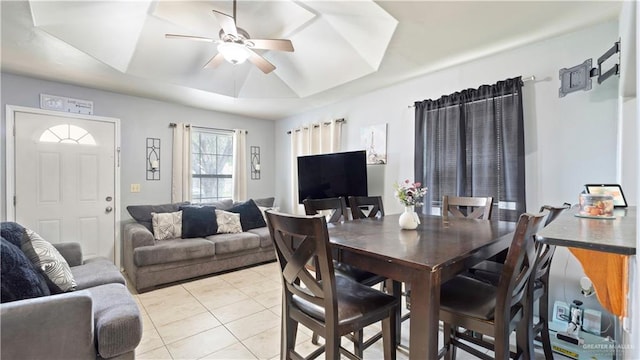 dining room with light tile patterned flooring, a ceiling fan, and a tray ceiling