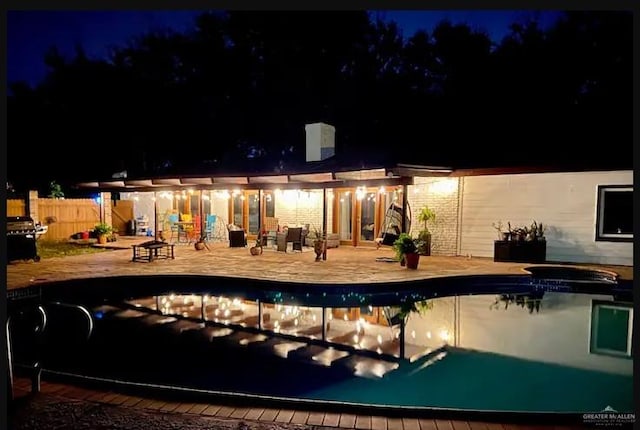 pool at night featuring a patio