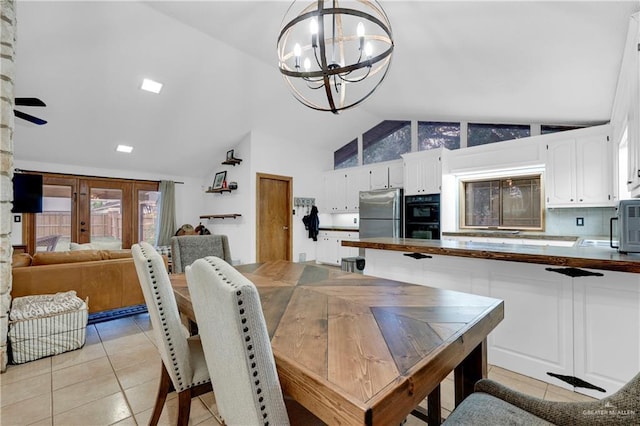 dining space featuring light tile patterned flooring, lofted ceiling, french doors, and an inviting chandelier