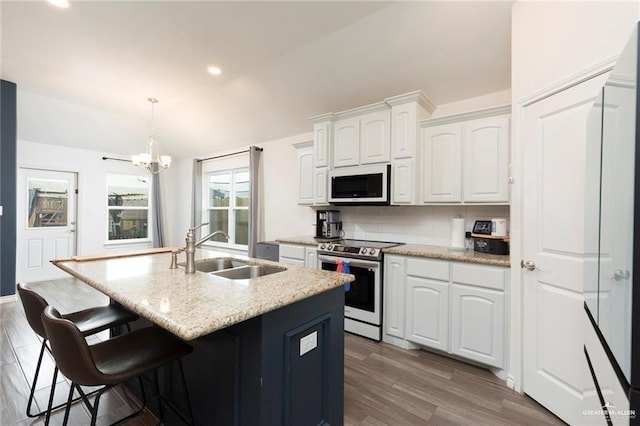 kitchen with electric range, a center island with sink, white microwave, white cabinetry, and a sink