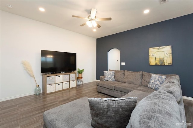 living area with baseboards, arched walkways, ceiling fan, wood finished floors, and recessed lighting