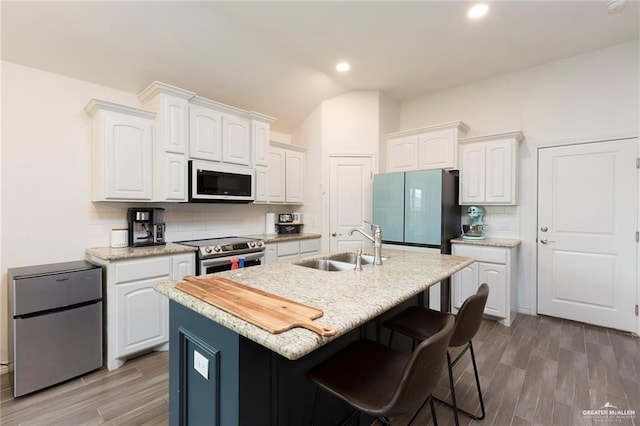 kitchen with white microwave, refrigerator, freestanding refrigerator, stainless steel electric range, and a sink