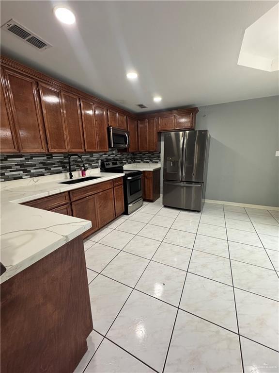 2110 Tiffany Dr, Mission, TX 78574 - kitchen featuring appliances with stainless steel finishes, a sink, decorative backsplash, light stone countertops, and light tile patterned floors