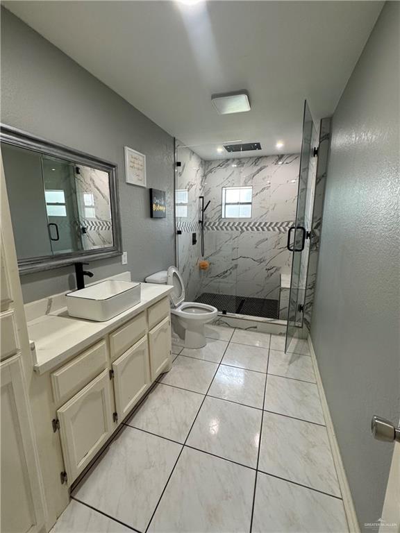 2110 Tiffany Dr, Mission, TX 78574 - bathroom with a marble finish shower, vanity, toilet, and baseboards