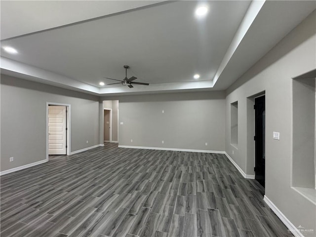 interior space with dark hardwood / wood-style floors, ceiling fan, and a tray ceiling