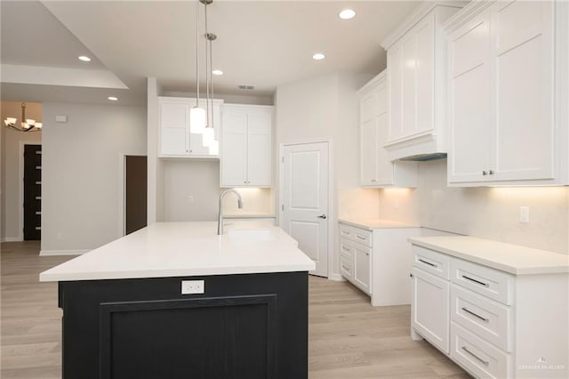 kitchen with sink, white cabinetry, and an island with sink