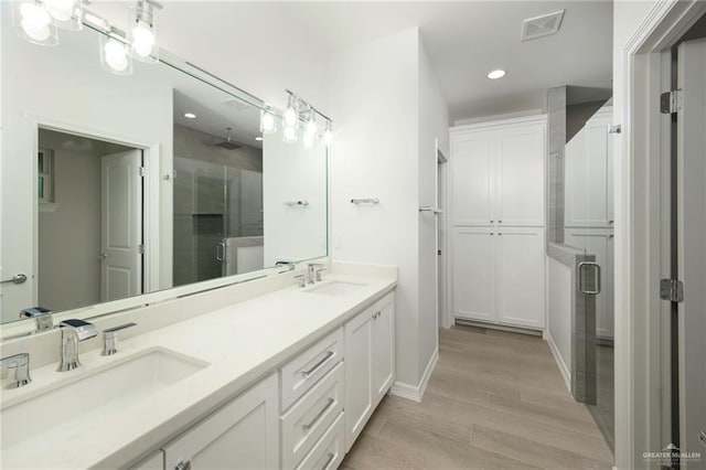 bathroom featuring wood-type flooring, vanity, and an enclosed shower