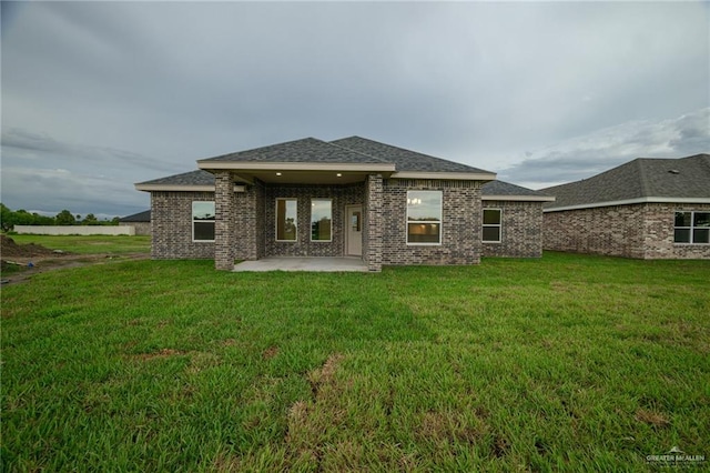 rear view of house featuring a lawn and a patio