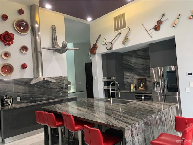 kitchen featuring a breakfast bar area, backsplash, dark stone countertops, and stainless steel appliances