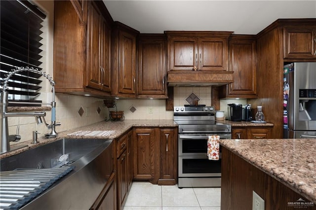 kitchen featuring decorative backsplash, stainless steel appliances, light stone counters, and light tile patterned flooring