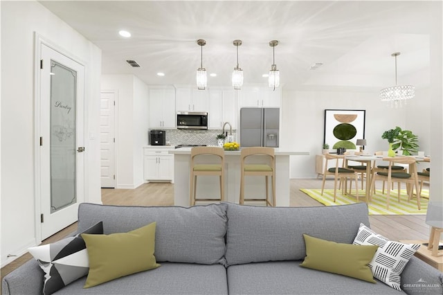 kitchen featuring decorative light fixtures, a breakfast bar area, white cabinets, and appliances with stainless steel finishes