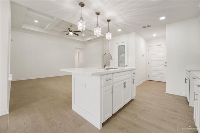 kitchen featuring white cabinetry, a kitchen island with sink, sink, and light hardwood / wood-style flooring