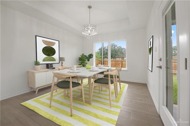 dining area featuring a raised ceiling, dark wood-type flooring, and a notable chandelier