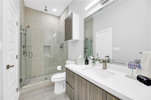 bathroom with vanity, toilet, and a shower with door