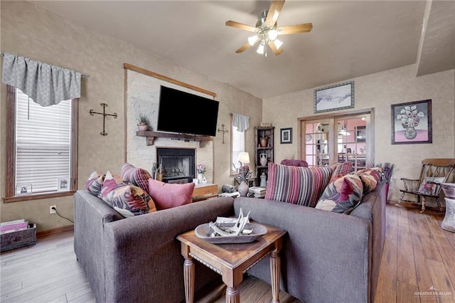 2724 Wildwood Dr, Weslaco, TX 78596 - living room featuring a ceiling fan, hardwood / wood-style floors, a stone fireplace, and baseboards