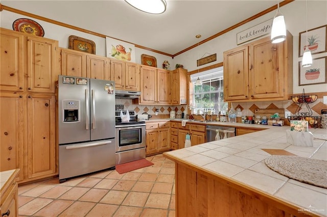 2724 Wildwood Dr, Weslaco, TX 78596 - kitchen with appliances with stainless steel finishes, under cabinet range hood, backsplash, tile countertops, and ornamental molding