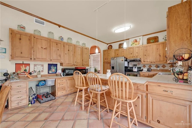 2724 Wildwood Dr, Weslaco, TX 78596 - kitchen with appliances with stainless steel finishes, under cabinet range hood, tile countertops, tasteful backsplash, and a kitchen breakfast bar